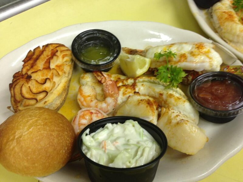 Seafood platter with shrimp, lobster with a side of cole slaw, potato and bread